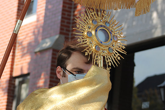 Father Dylan Schrader carries the Most Blessed Sacrament in solemn procession.